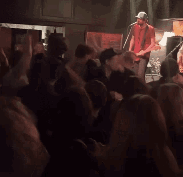 a man playing a guitar in front of a crowd of people