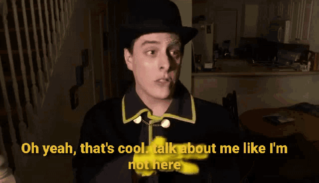 a man wearing a hat and yellow gloves says " oh yeah that 's cool talk about me like i m not here "