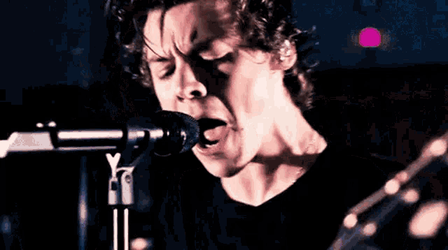a man in a black shirt is singing into a microphone .
