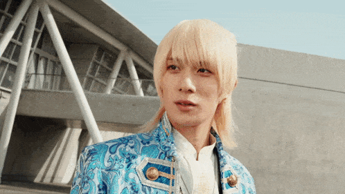 a man with blonde hair wearing a blue jacket