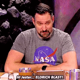 a man wearing a nasa t-shirt is sitting at a table