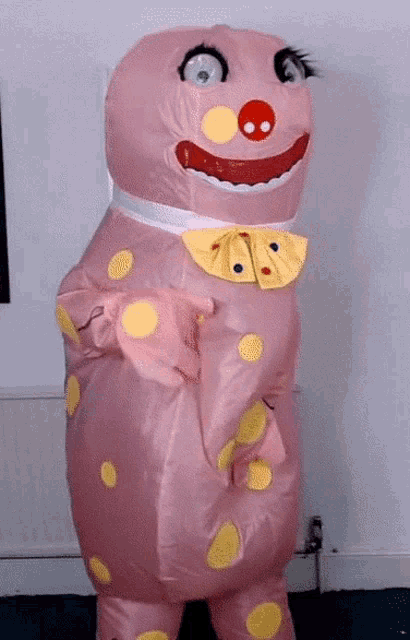 a pink inflatable clown costume with yellow polka dots and a red nose