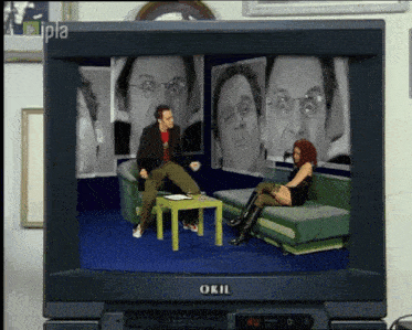 a television screen shows a man and a woman sitting on a couch and the word okil on the bottom of the screen