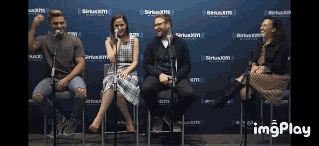 a group of people are sitting in front of a siriusxm wall