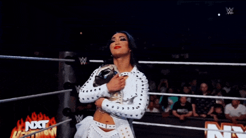 a woman in a wrestling ring is holding a championship belt .