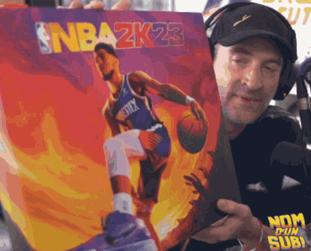 a man is holding a nba 2k23 basketball game