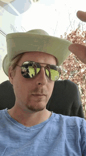 a man wearing a cowboy hat and sunglasses is taking a picture of himself