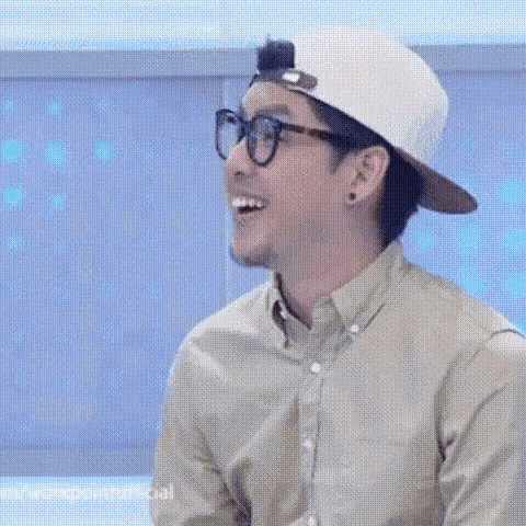 a man wearing glasses and a hat is laughing .