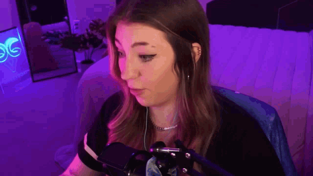 a woman is sitting in front of a microphone in a room with purple lights .