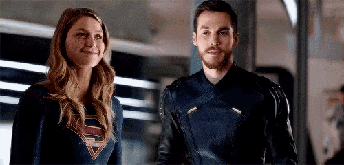 a man and a woman are standing next to each other in a room and smiling .