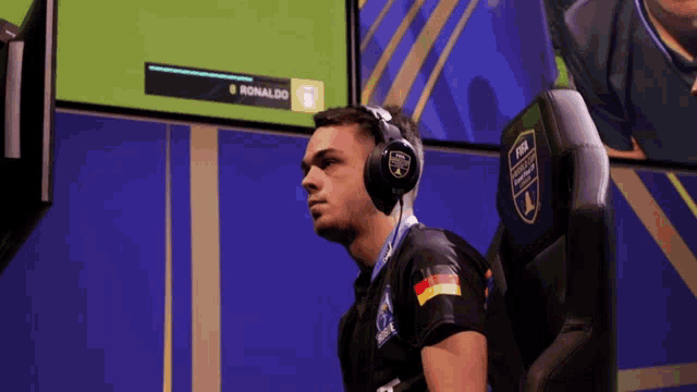 a man wearing headphones sits in front of a screen with the name ronaldo on it