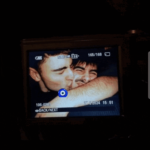 a camera screen shows a man kissing another man 's arm