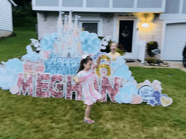 a little girl stands in front of a sign that says meghan on it