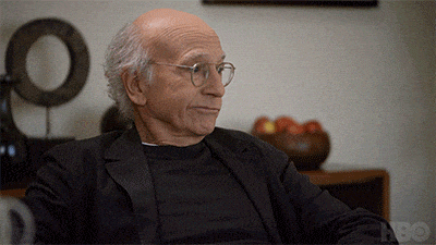 a man wearing glasses and a black shirt is sitting in front of an hbo sign