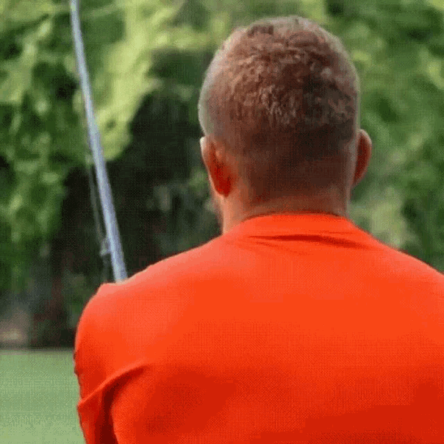 a man in an orange shirt holds a fishing rod