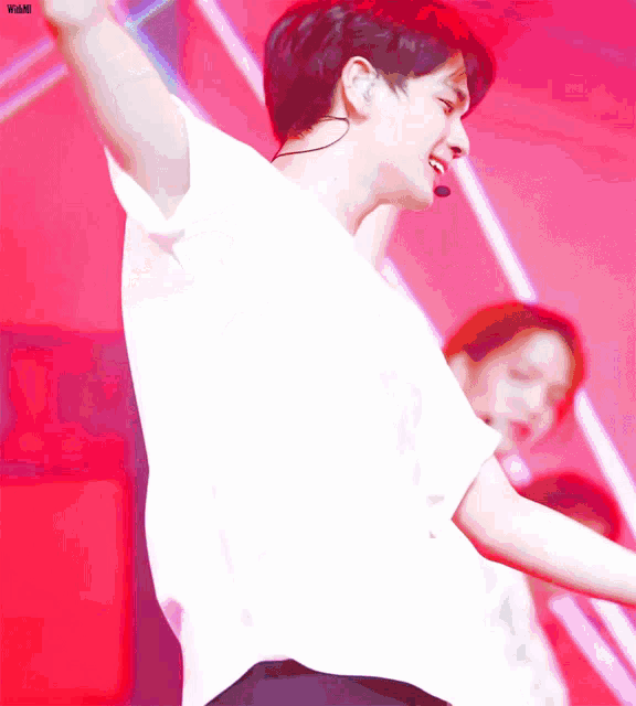 a man in a white shirt with a microphone on his ear is dancing on a stage