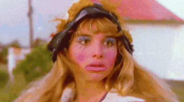 a woman with pink makeup and a hat on her head .