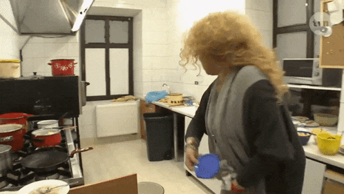 a woman standing in a kitchen with a blue cup