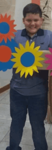 a boy in a blue shirt is holding two paper flowers in his hands