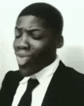 a black and white photo of a man in a suit and tie making a face .