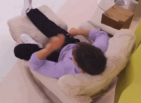 a man in a purple shirt is laying on a chair .