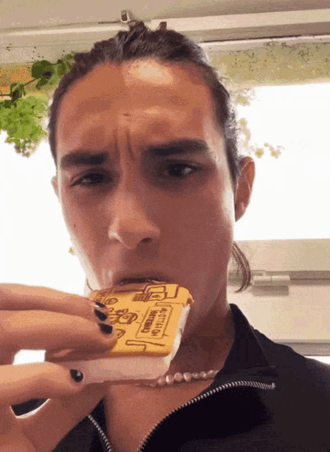 a man with black nails is eating a sandwich that says ice cream