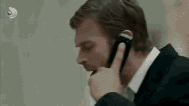 a man is talking on a cell phone while wearing a suit .