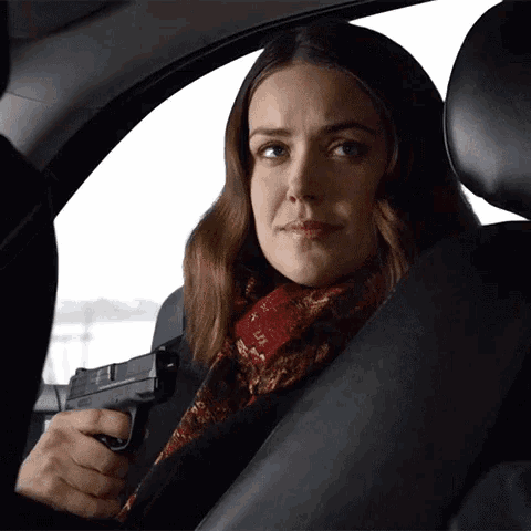 a woman in a car is holding a gun in her right hand
