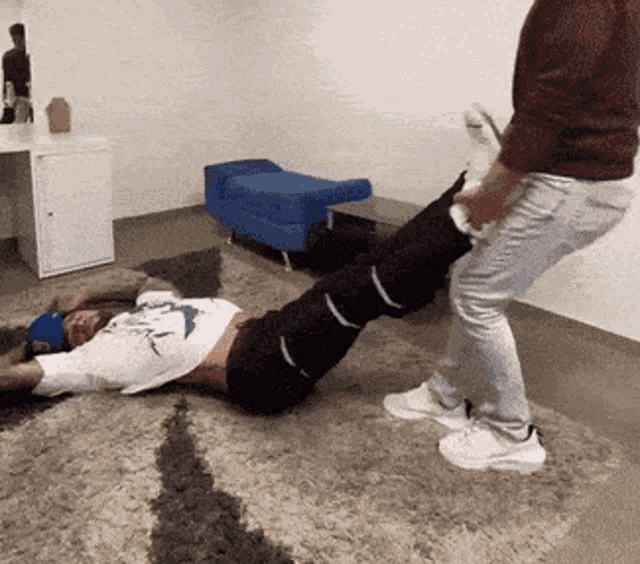 a man is laying on the floor with his legs crossed while another man stands next to him