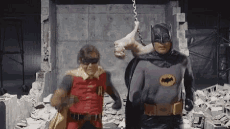 batman and robin are standing next to each other in a building .