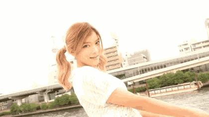a woman in a white shirt is standing in front of a body of water