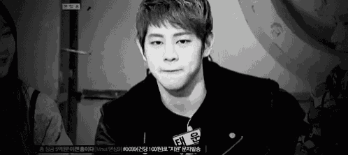 a black and white photo of a young man in a leather jacket making a face .