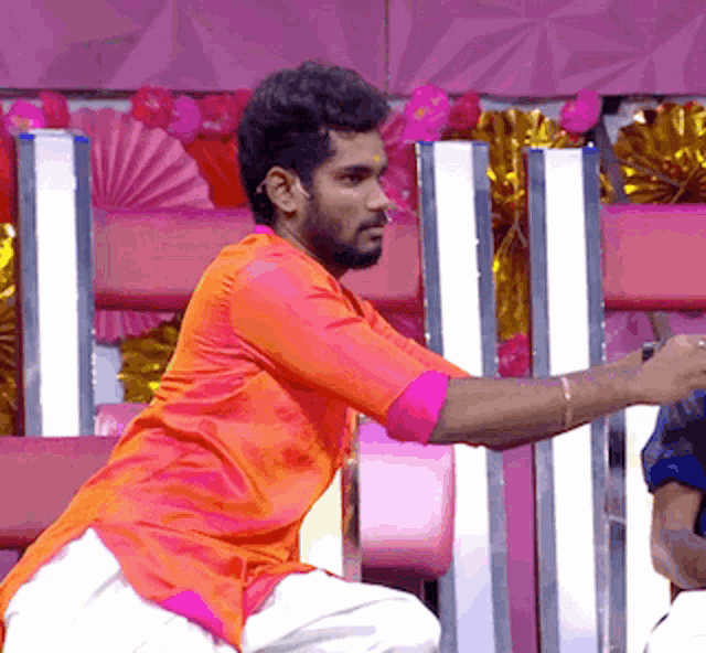 a man in an orange shirt and white pants is kneeling down