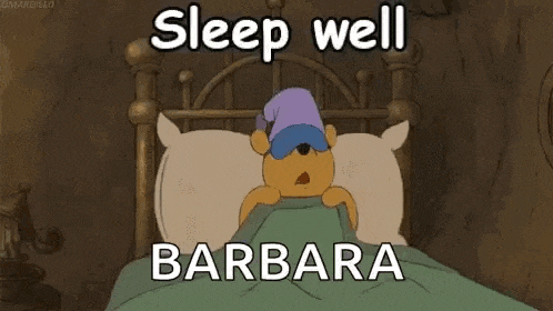 winnie the pooh is laying in a bed with a sleep cap on his head .