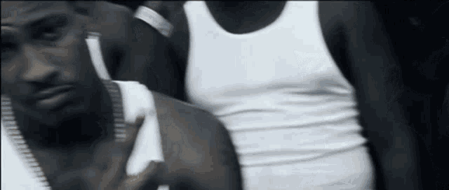 a man in a white tank top has a tattoo on his chest