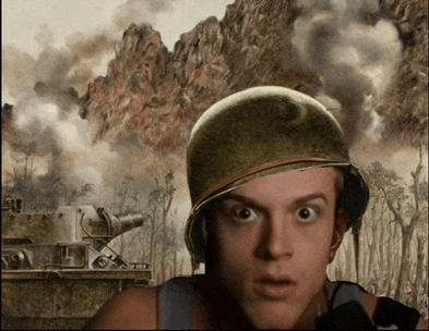 a man wearing a helmet looks surprised in front of a battle scene