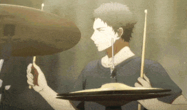a man in a black shirt is holding a pair of cymbals while playing drums .