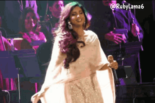 a woman in a white dress is singing into a microphone with rubylama6 written on the bottom right