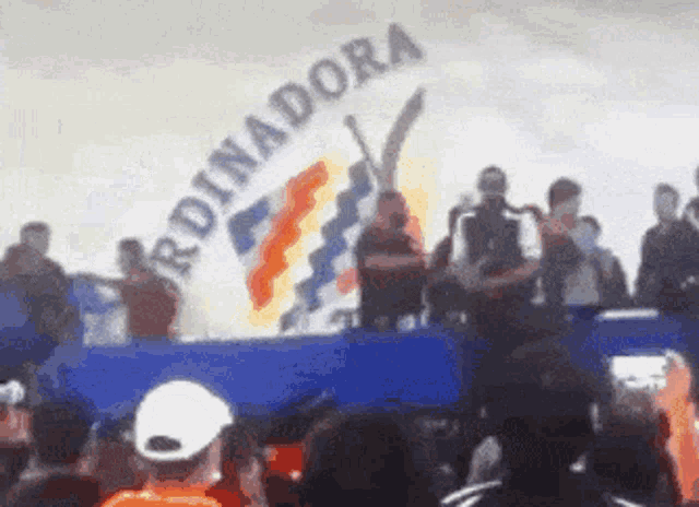 a crowd of people are gathered in front of a banner that says ' rdinadora '