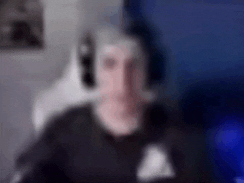 a blurry picture of a man wearing headphones in front of a computer monitor .