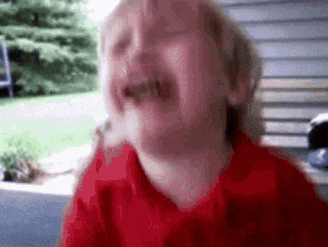 a young boy in a red shirt is crying with his eyes closed .