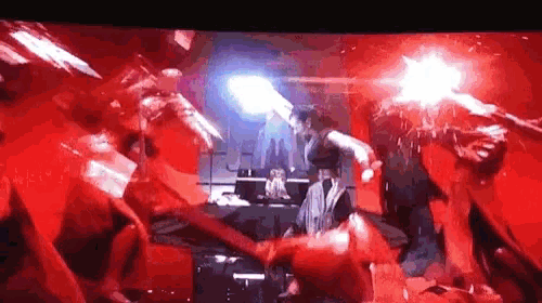 a group of people are standing in a room with red lights .