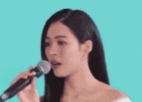 a woman is singing into a microphone while making a funny face .