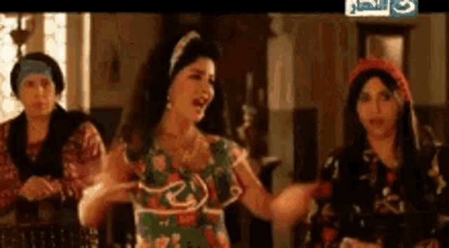 a group of women are standing next to each other in a room and one of them is singing .