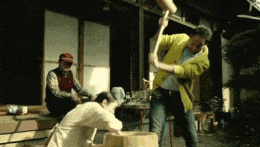 a man in a yellow cardigan is using a hammer to pound a woman