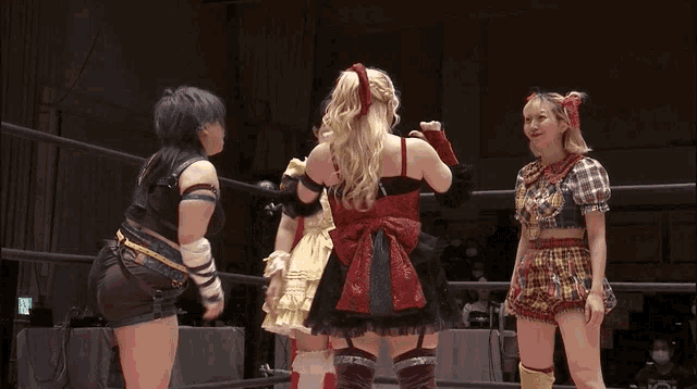 a group of women are standing in a wrestling ring and one of them is wearing a plaid skirt