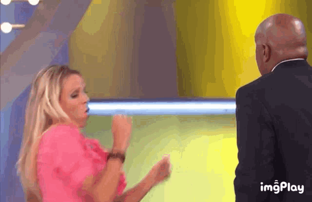 a woman in a pink dress is dancing in front of a man in a suit ..