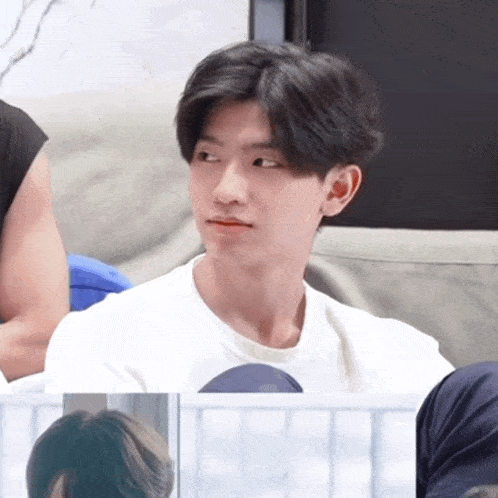 a young man sitting on a couch with a white shirt on