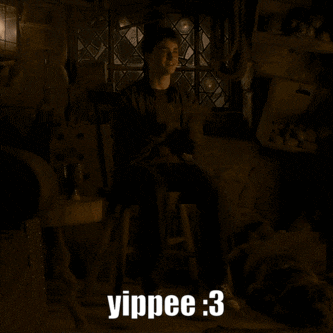 harry potter is sitting on a stool in a dark room
