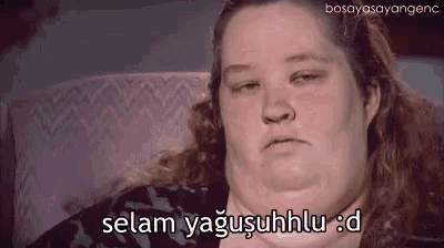 a woman with a very large neck is sitting in a chair and making a sad face .